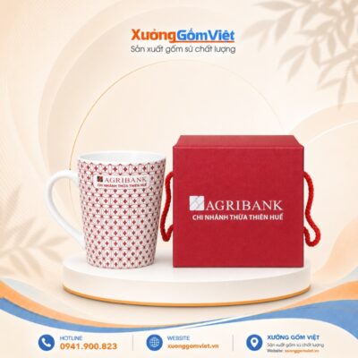 Ly sứ in logo AGRIBANK CHI NHÁNH THỪA THIÊN HUẾ dáng trụ có quai màu trắng họa tiết hoa lưới đỏ M115